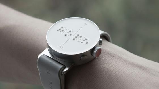 Das Bild zeigt die Dot Watch mit der Blinde lBücher lesen